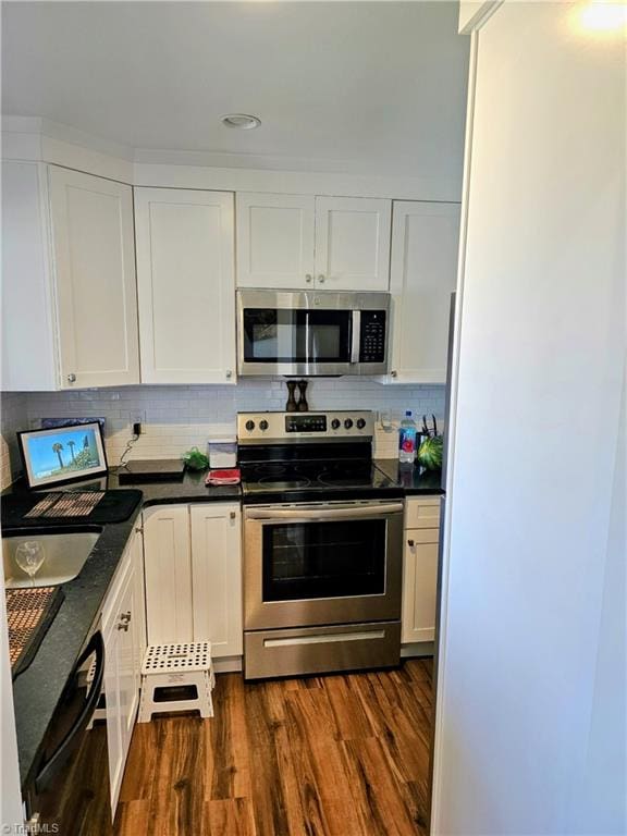 kitchen with white cabinets, appliances with stainless steel finishes, and dark hardwood / wood-style flooring