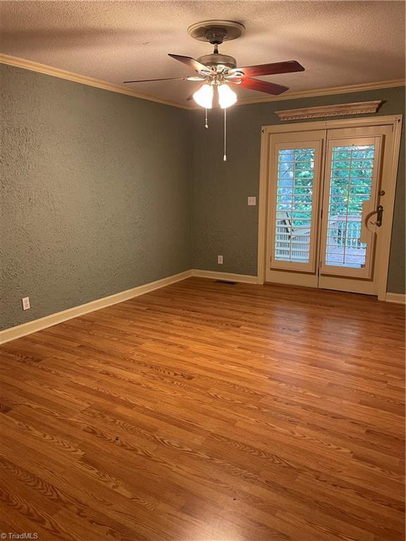 unfurnished room with wood-type flooring, crown molding, ceiling fan, and a textured ceiling