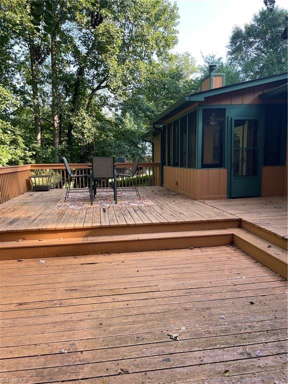 wooden deck featuring outdoor dining area and a sunroom