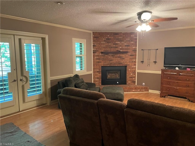 living room featuring a textured ceiling, a fireplace, wood finished floors, and crown molding