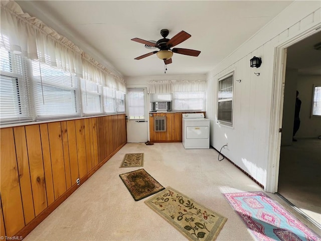 kitchen featuring ceiling fan, cooling unit, washer / dryer, light colored carpet, and wood walls