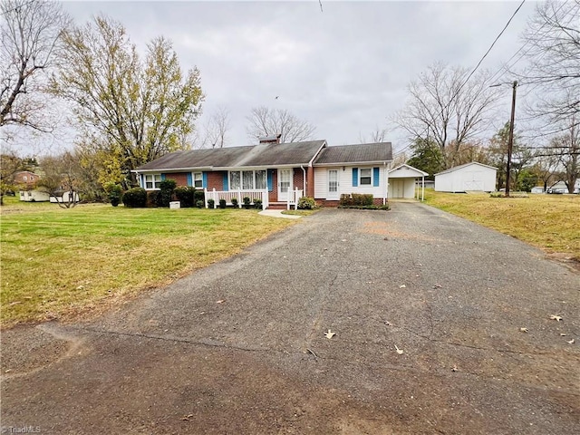 single story home featuring a porch, an outbuilding, a garage, and a front yard