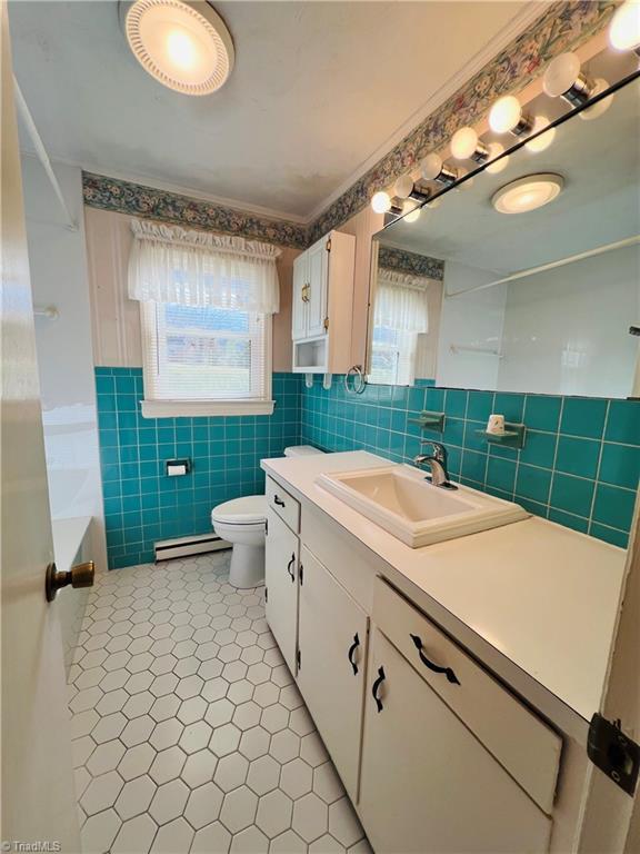 full bathroom featuring baseboard heating, tile walls, vanity, shower / bathtub combination, and toilet