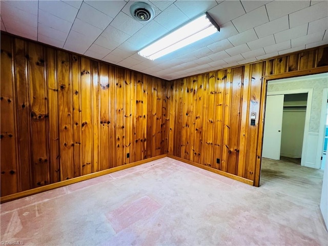 basement featuring light carpet and wooden walls