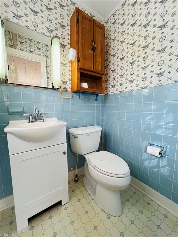 bathroom with vanity, tile walls, crown molding, and toilet