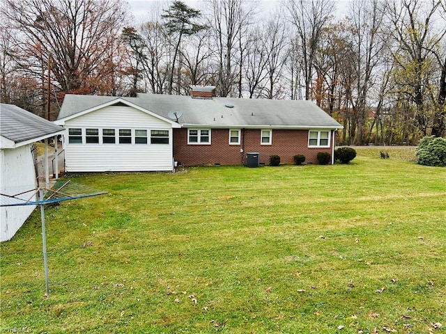 back of property featuring central AC unit and a yard