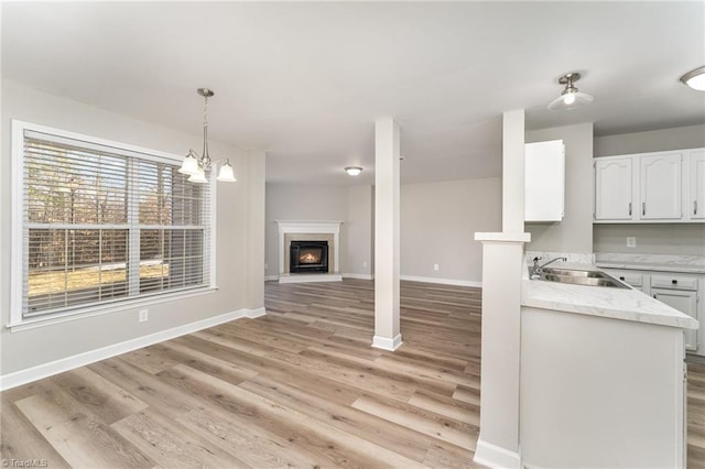 kitchen featuring white cabinets, a healthy amount of sunlight, pendant lighting, and sink