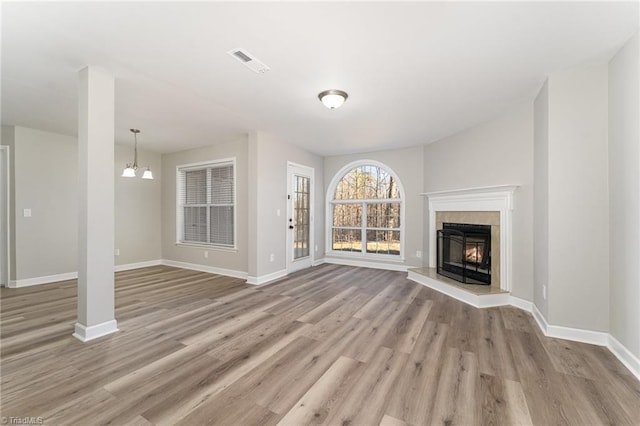 unfurnished living room featuring light hardwood / wood-style floors, a notable chandelier, and a fireplace