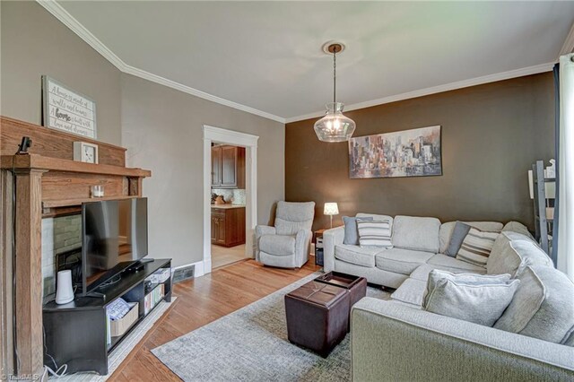 living room with crown molding, light wood-style flooring, a fireplace, and baseboards