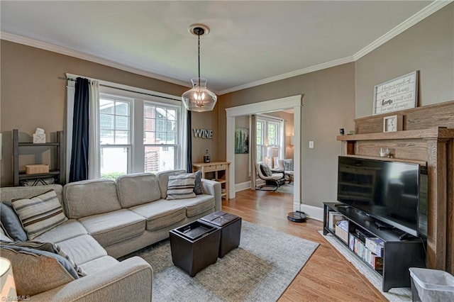 living area with crown molding, light wood-style flooring, and baseboards