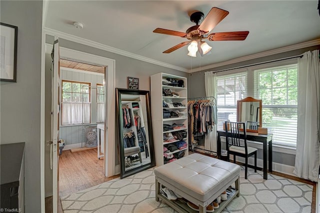 bedroom with light wood-style floors, ornamental molding, baseboards, and a ceiling fan