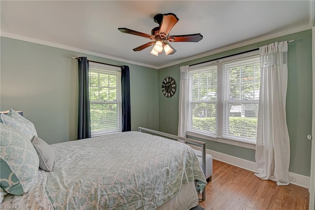 bedroom with baseboards, crown molding, wood finished floors, and a ceiling fan