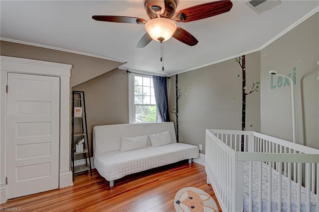 bedroom with light wood-style floors, ornamental molding, and a ceiling fan