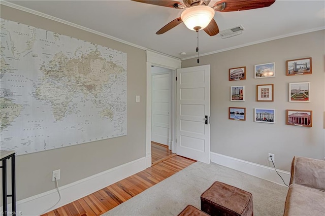living area with a ceiling fan, ornamental molding, baseboards, wood finished floors, and carpet floors