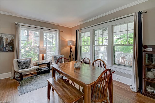 dining space with wood finished floors, crown molding, and baseboards
