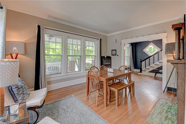 dining area with light wood finished floors, crown molding, baseboards, and stairway