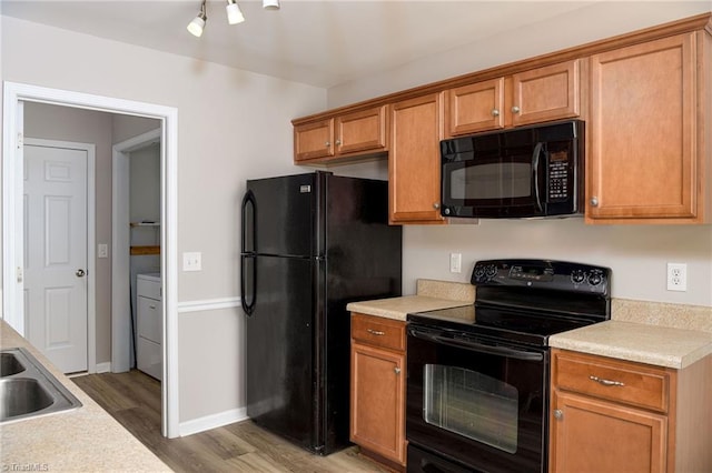 kitchen with baseboards, light wood-style floors, light countertops, brown cabinets, and black appliances