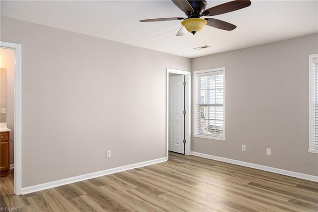 empty room featuring a ceiling fan, light wood-type flooring, visible vents, and baseboards