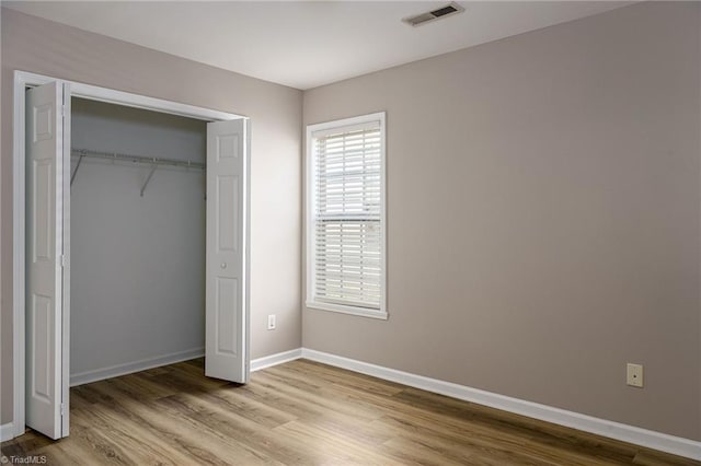 unfurnished bedroom featuring a closet, baseboards, visible vents, and light wood finished floors