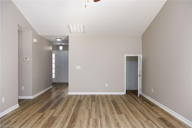 empty room with ceiling fan, wood finished floors, visible vents, and baseboards