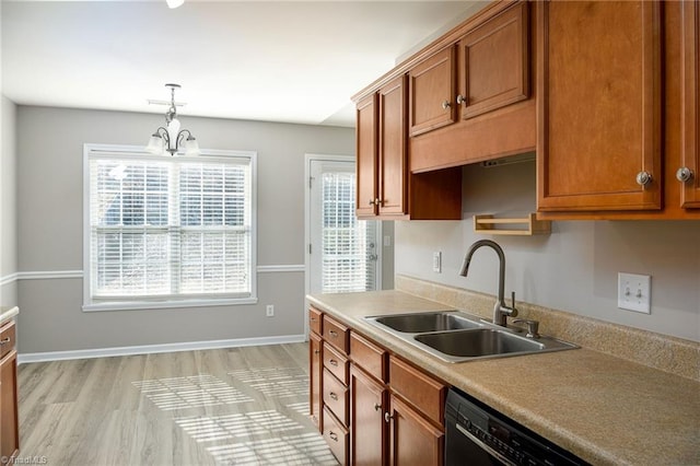 kitchen featuring hanging light fixtures, black dishwasher, brown cabinetry, and a sink