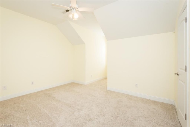 additional living space with lofted ceiling, light colored carpet, visible vents, a ceiling fan, and baseboards