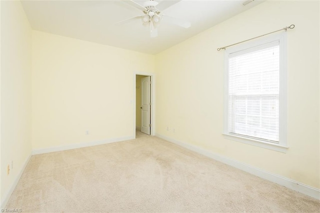 unfurnished room with light carpet, ceiling fan, baseboards, and a wealth of natural light