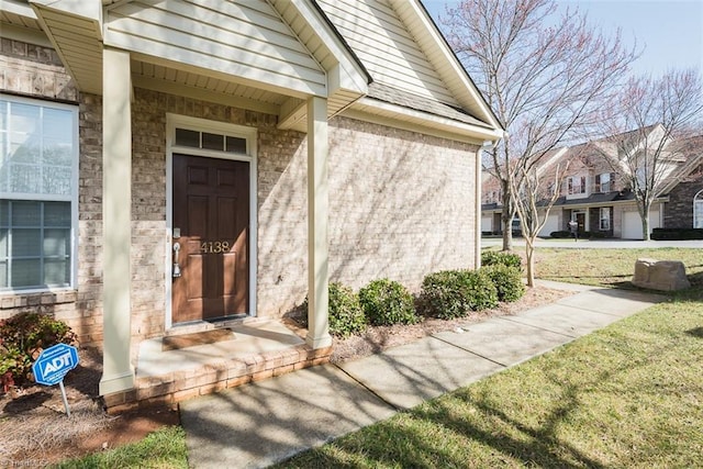 entrance to property featuring a yard and brick siding