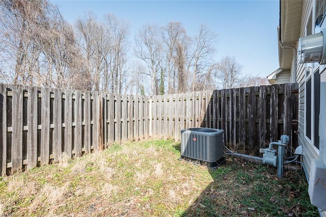 view of yard with a fenced backyard and central AC