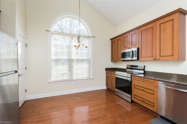 kitchen featuring vaulted ceiling, stainless steel appliances, dark wood-style flooring, and brown cabinetry