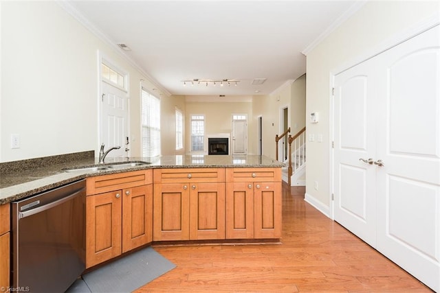 kitchen with crown molding, light wood-style floors, brown cabinetry, a sink, and dishwasher