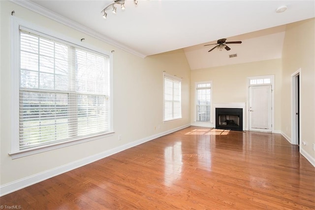 unfurnished living room with lofted ceiling, a fireplace with flush hearth, ceiling fan, wood finished floors, and baseboards