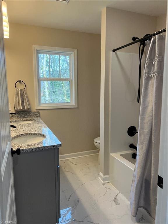 bathroom featuring marble finish floor, double vanity, shower / bath combo, a sink, and baseboards