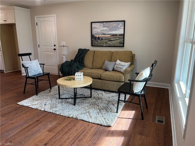 living area featuring dark wood-style flooring, visible vents, and baseboards