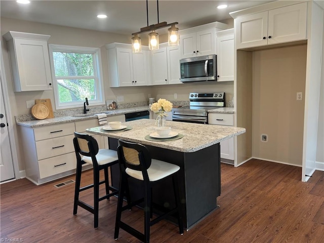 kitchen with visible vents, stainless steel appliances, white cabinets, and a center island