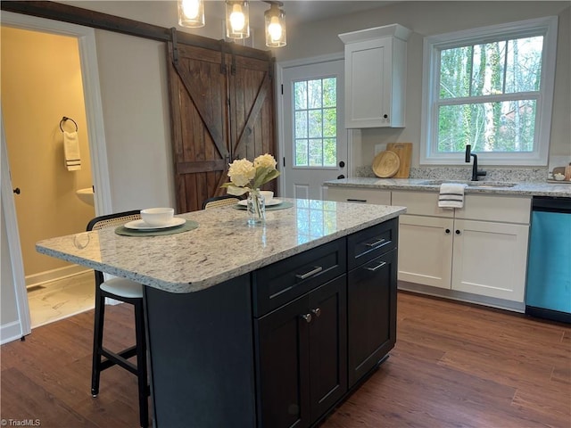 kitchen with decorative light fixtures, white cabinets, a kitchen island, a sink, and dishwasher