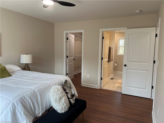 bedroom featuring connected bathroom, baseboards, a closet, dark wood-style floors, and a walk in closet