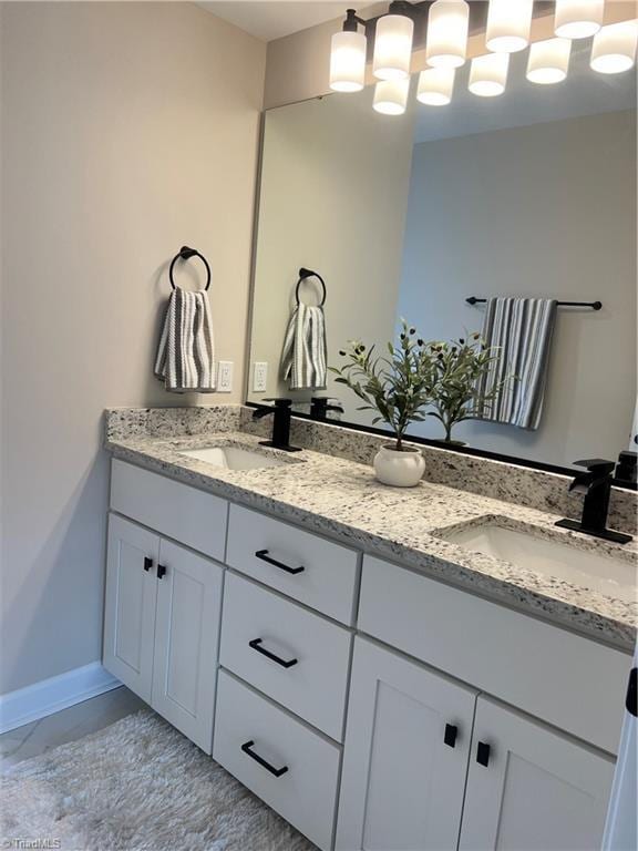 full bathroom featuring double vanity, a sink, and baseboards