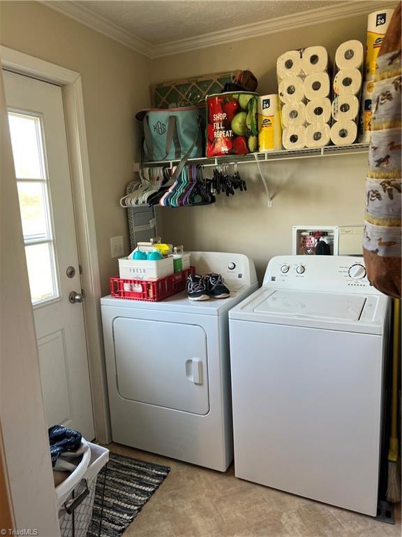 clothes washing area featuring separate washer and dryer and ornamental molding