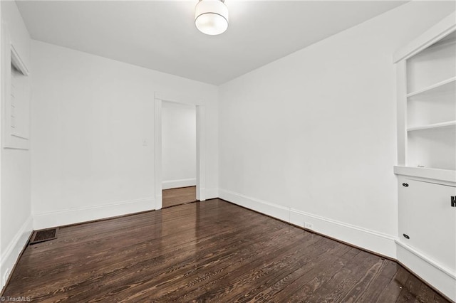 unfurnished room featuring built in features and dark hardwood / wood-style floors