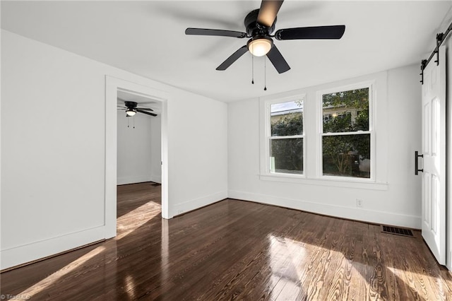 unfurnished bedroom with ceiling fan, dark hardwood / wood-style flooring, and a barn door