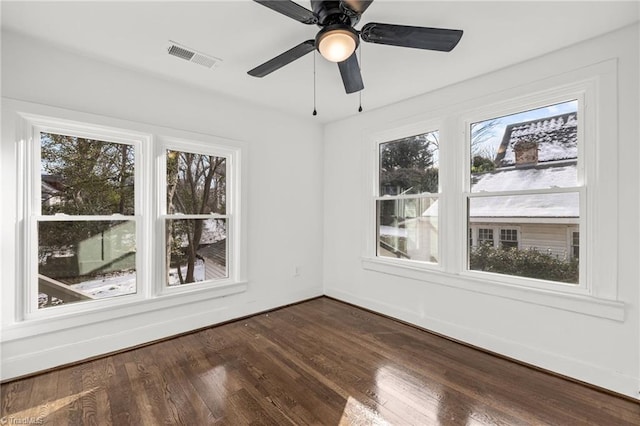 spare room featuring ceiling fan, a healthy amount of sunlight, and wood-type flooring