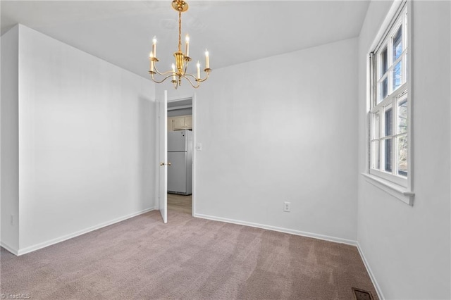 carpeted spare room with a notable chandelier, visible vents, and baseboards