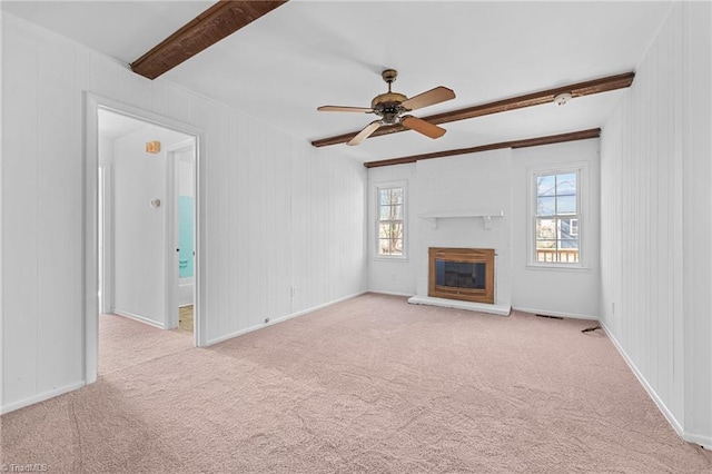 unfurnished living room with baseboards, ceiling fan, beamed ceiling, carpet flooring, and a glass covered fireplace