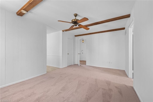 unfurnished room with beam ceiling, wooden walls, ceiling fan, and carpet