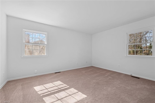 unfurnished room featuring visible vents, baseboards, and carpet flooring