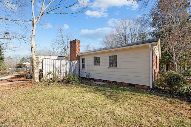 rear view of property with crawl space, a yard, and a chimney