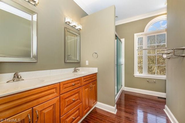 full bath featuring crown molding, a sink, baseboards, and wood finished floors