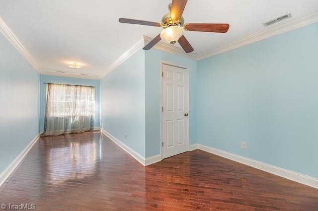 empty room with ornamental molding, visible vents, baseboards, and wood finished floors