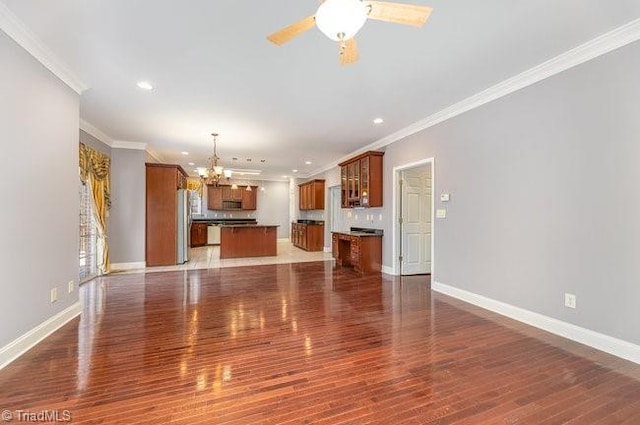 unfurnished living room with baseboards, wood finished floors, ceiling fan with notable chandelier, crown molding, and recessed lighting